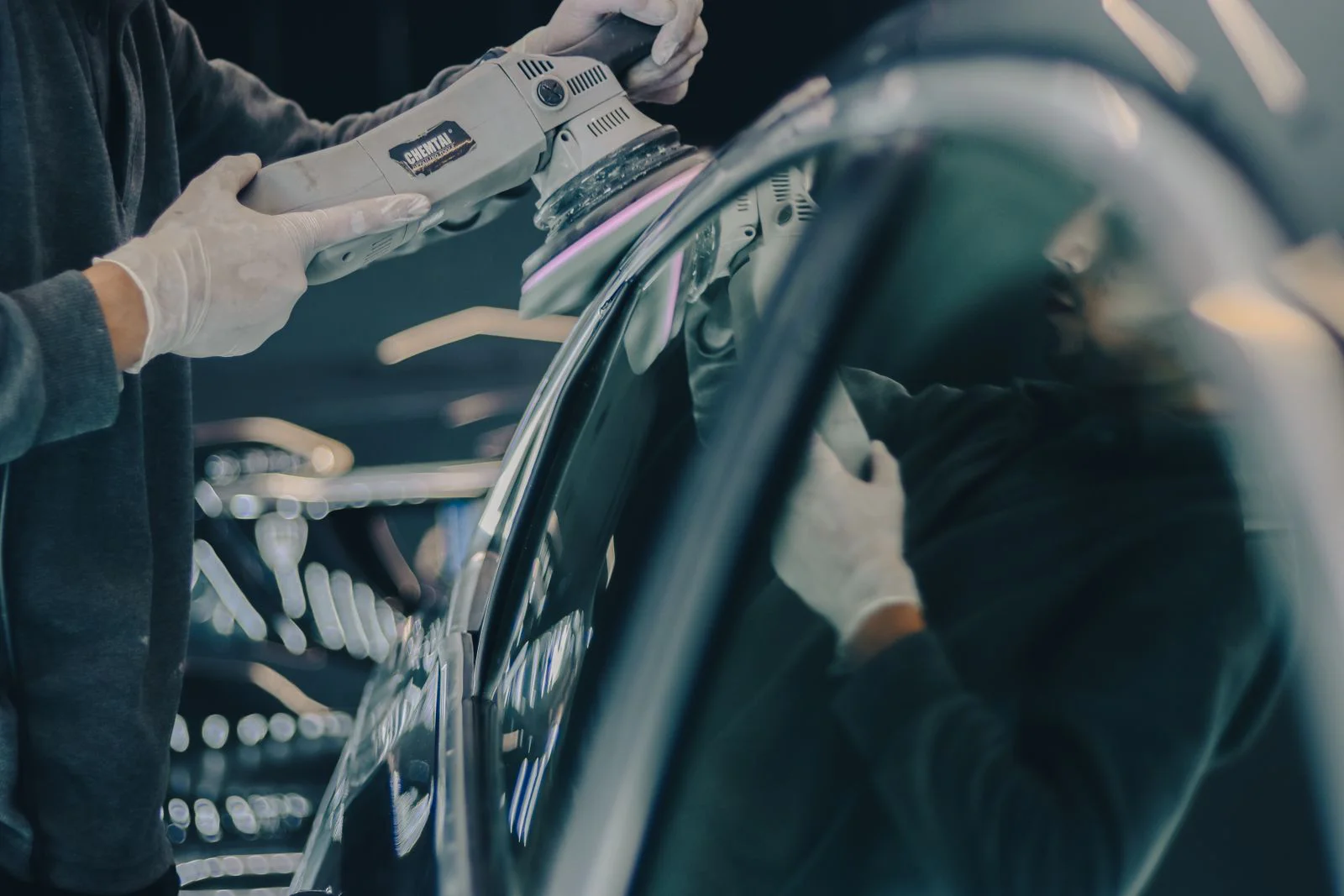 Detailer machine polishing the paint on a black car